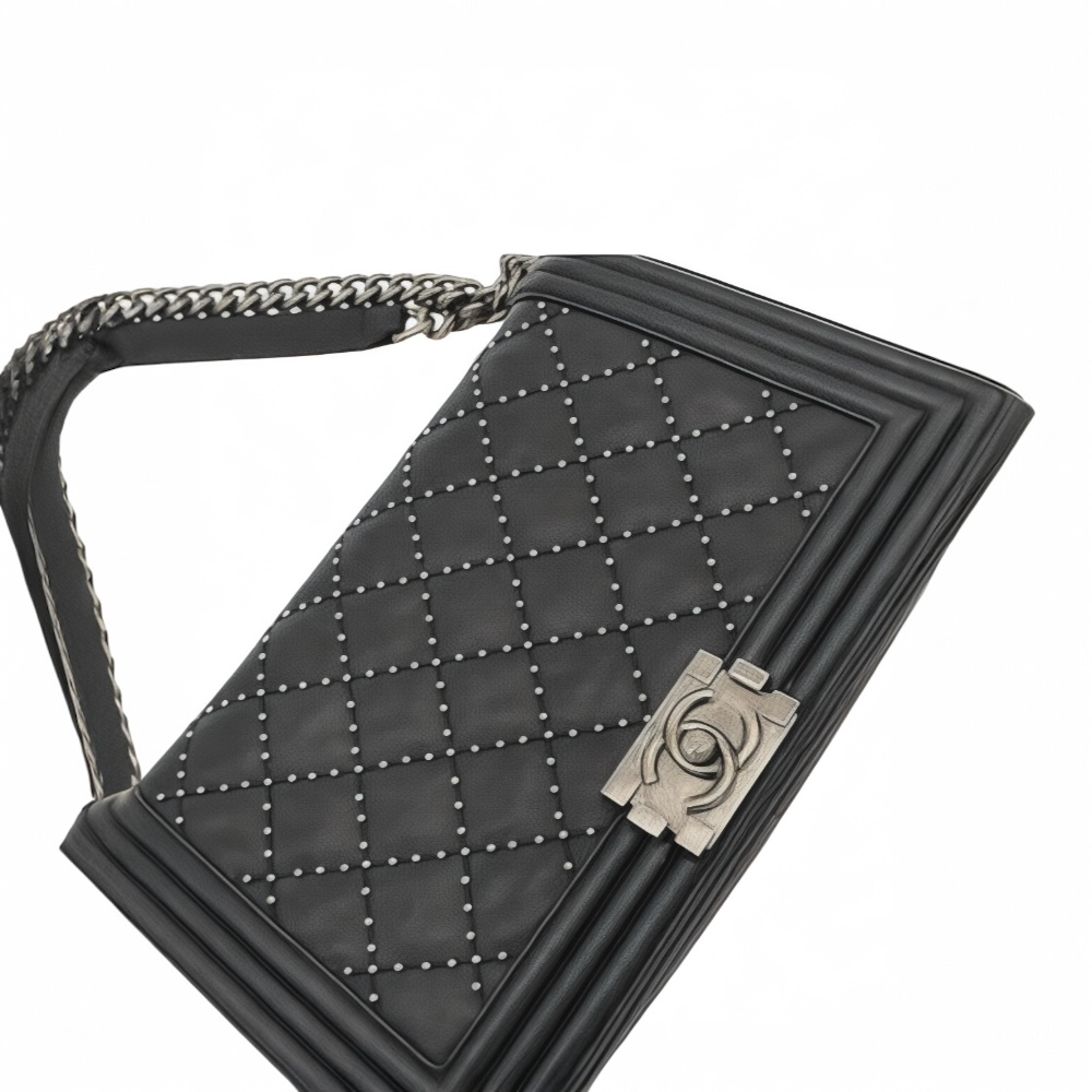 Flat view of black medium Chanel Boy bag bag with silver chain strap and Chanel logo on a white background